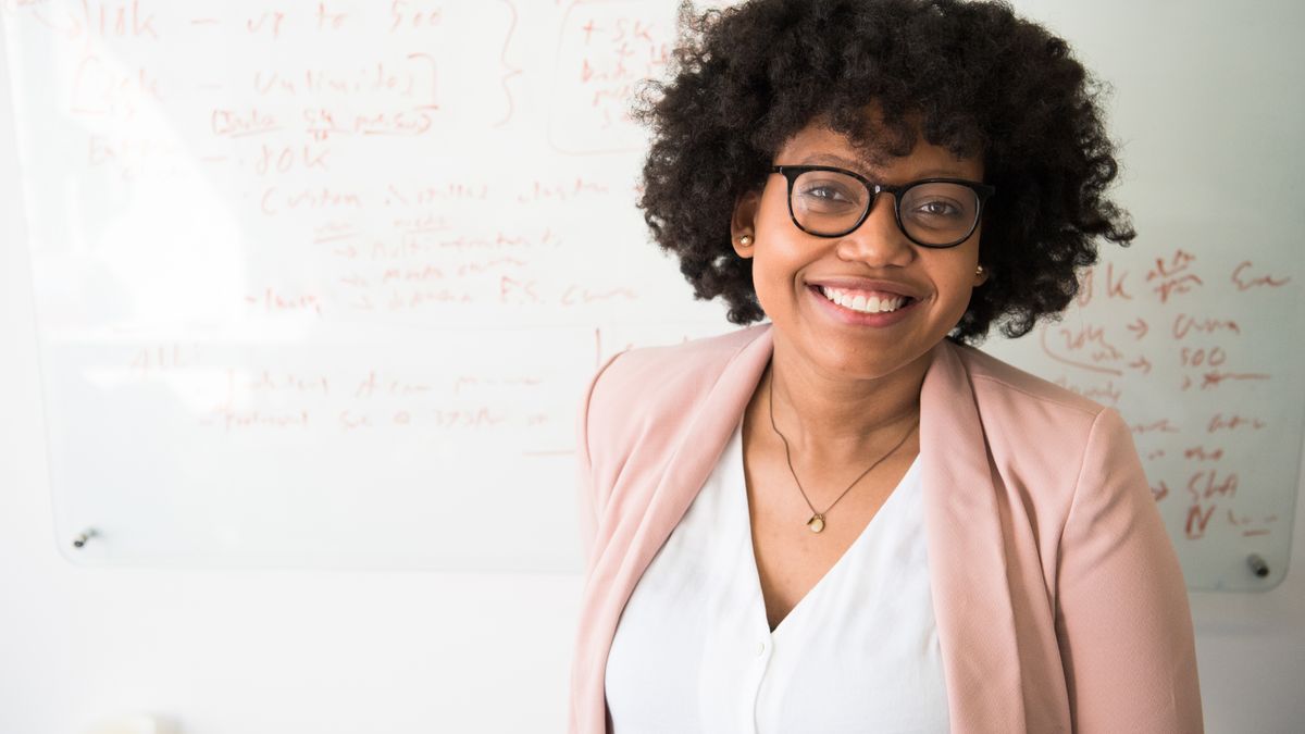 Femme professionnelle en blazer devant un tableau blanc en réflexion